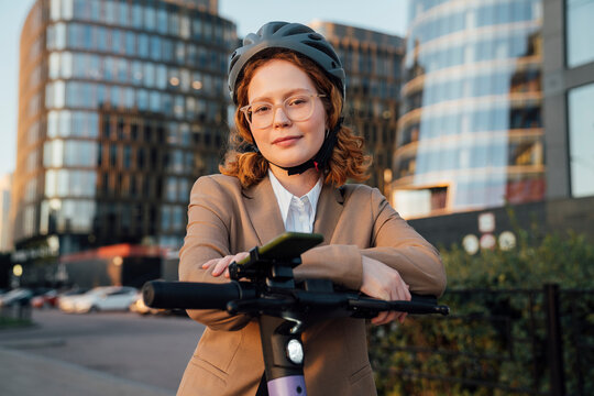Beautiful businesswoman with eyeglasses leaning on push scooter