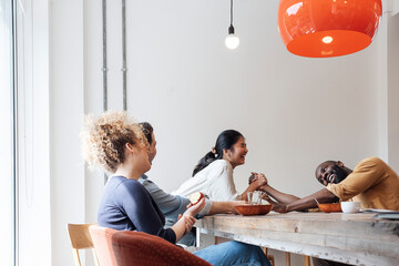 Businesswoman winning at arm wrestling over male colleague at lunch break