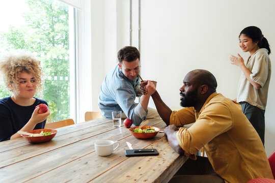 Two businessman arm wrestling in staff room at lunch break