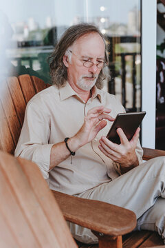 Senior man sitting on chair and using tablet PC at home terrace