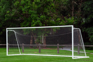 Side of football of soccer goal post with net in focus. Field out of focus. Sport background and...