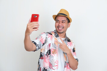 Asian man wearing beach shirt taking a selfie with his handphone