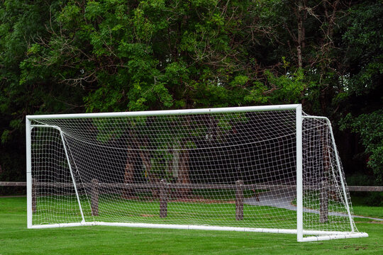Side of football of soccer goal post with net in focus. Field out of focus. Sport background and equipment.