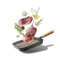Flying raw beef steaks, seasoned with herbs, oil and spices with grill pan and kitchen utensils isolated on transparent background, top view. Levitation food concept