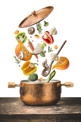 Healthy vegetarian cooking with pumpkin and various flying chopped vegetables ingredients, cooking pot and spoon on wooden table desk , isolated on transparent background, front view. 
