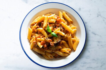 Pasta alla normal - Italian pasta with eggplant, tomato sauce and Parmesan cheese on dark background. Top view. Healthy food.