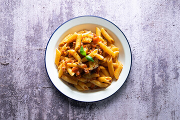 Pasta alla normal - Italian pasta with eggplant, tomato sauce and Parmesan cheese on dark background. Top view. Healthy food.