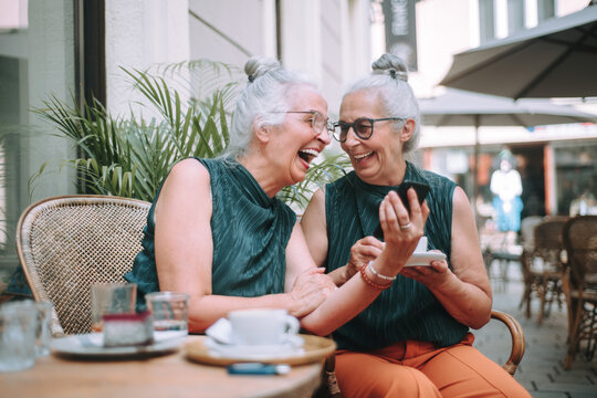 Happy Senior Women Twins Having Coffee Break In City, Smiling And Talking.