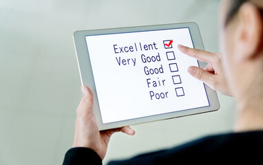 Close-up of woman filling online customer service satisfaction survey on digital tablet