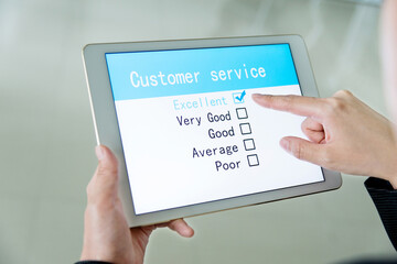 Close-up of woman filling online customer service satisfaction survey on digital tablet