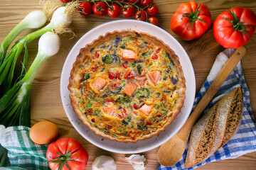 Salmon and vegetable quiche. Traditional French recipe with fish and fresh vegetables with handmade dough and egg.