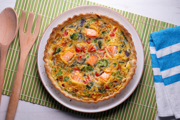 Salmon and vegetable quiche. Traditional French recipe with fish and fresh vegetables with handmade dough and egg.