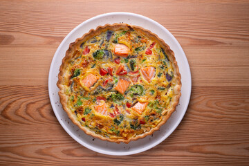 Salmon and vegetable quiche. Traditional French recipe with fish and fresh vegetables with handmade dough and egg.