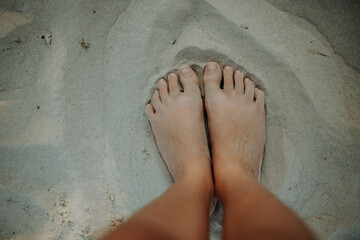 Close-up of barefoot legs walking in sand. Concept of healthy feet.