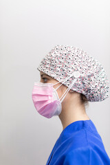 Portrait of a white dentist woman posing for the camera, wearing mask, medical hat and uniform...