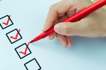 Closeup of hand with red pencil marking check box