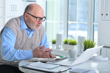 Fototapeta na wymiar Emotional senior man reading newspaper at home