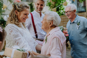 Mature bride and groom receiving congratulations at wedding reception outside in the backyard. - obrazy, fototapety, plakaty