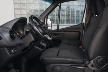 Luxury van driver seats with dashboard, multimedia control screen, and steering wheel. The cockpit of a modern luxury minivan