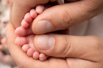 Mother and father are doing massage on her baby foot. Closeup baby feet in mother hands. Prevention of flat feet, development, muscle tone, dysplasia. Family, love, care, and health concepts.
