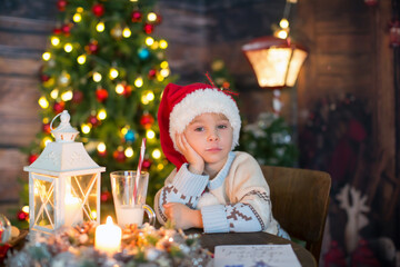 Cute toddler child, boy in a Christmas outfit, playing in a wooden cabin on Christmas, decoration around him