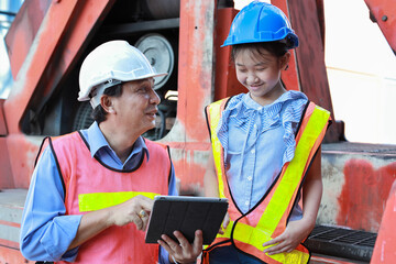 Asian foreman father and his daughter sitting on forklift while teaching little girl. Engineer dad...