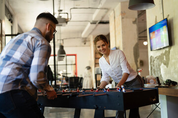 Colleagues having fun at work. Businessman and businesswoman playing table soccer..