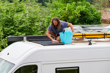 Man cleaning RV van with solar battery