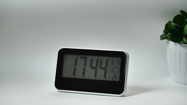 Modern digital clock, alarm clock with a thermometer, hydrometer standing on white background. Time concept.