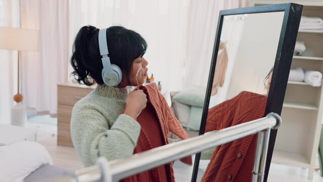 Energy, music and woman getting ready in a mirror with clothes and dance, happy and excited in her bedroom. Radio, podcast and online streaming by black female choosing an outfit while having fun