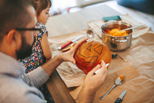 Father and daughter carving Halloween pumpkin