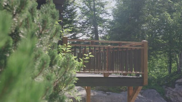 Panning on wooden deck on wood cabin in pine tree forest in mountains in summer