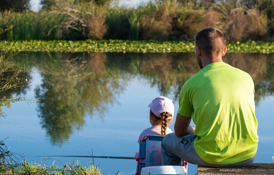 Father and daughter fishing on the banks of a river