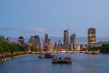 Fototapeta premium A view along the river Thames, to the skyscrapers of Vauxhall and Battersea, at night. The building are lit up
