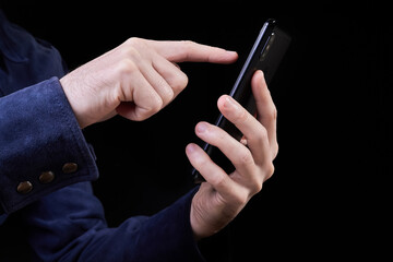 Man presses his finger on the screen of a smartphone on a dark background