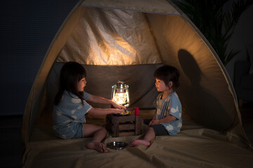 Obraz na płótnie Canvas 自宅の部屋でテントを張ってキャンプ遊びをしている2人の女の子の姉妹