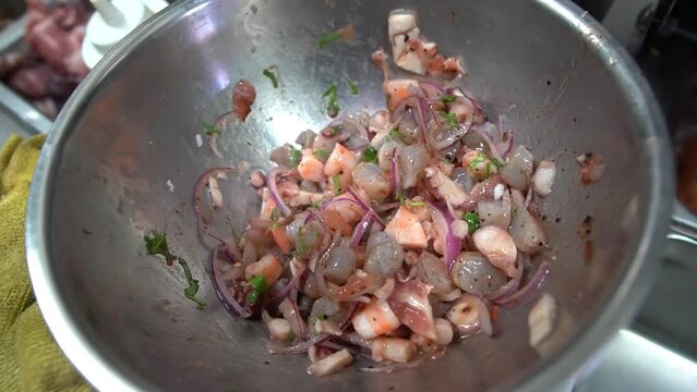 preparation in an aluminum bowl ceviche type mexico with fresh vegetables such as onion, cilantro, lemon, pepper and seafood octopus, shrimp and mojarra