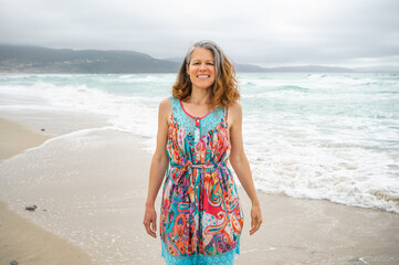 Woman with gray hair smiles at camera on a beach