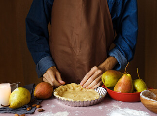 Women's hands, dough and flour A woman in an apron prepares dough for a pie. Close - up . Rustic style