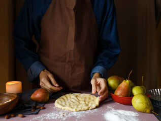 Women's hands, dough and flour A woman in an apron prepares dough for a pie. Close - up . Rustic style
