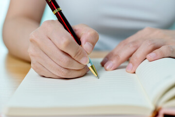 Hands writing in notepad on wooden table