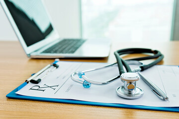 Stethoscope with clipboard and laptop on docotr desk