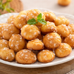 Delicious French Chouquette Choux Pastry dessert Pearl Sugar Puff on wooden table background.