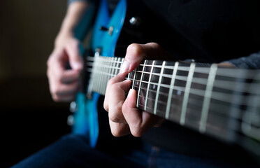 Fototapeta premium guitarist man playing guitar, a man sitting and practicing electric guitar on dark background