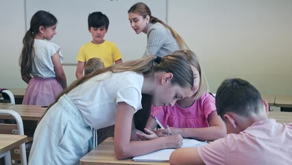Schoolchildren performing group tasks in classroom. They discuss questions together in each team.