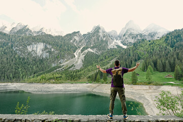 Back of man with backpack against lake and mountains at Vorderer Gosausee, Gosau, Upper Austria.