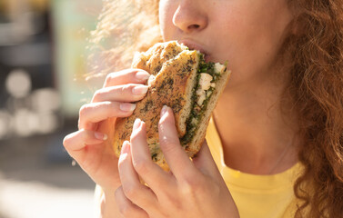 Young woman eating fast food, sandwich , close-up. Woman to eat lunch in cafe.