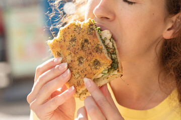 Young woman eating fast food, sandwich , close-up. Woman to eat lunch in cafe.