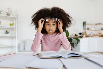 Shocked black child schooler doing homework at home