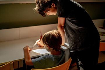 Two brothers draw with colored pencils, the older brother teaches the younger one to draw, the concept of family and friendship